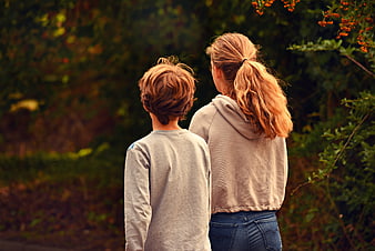 Two Siblings Walking Together in Autumn Forest