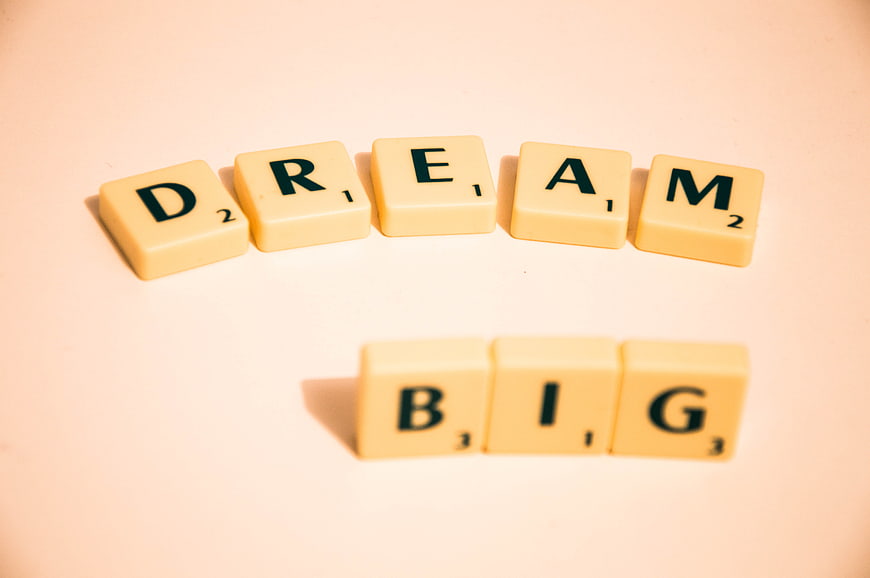 Scrabble Tiles Spelling Dream Big on Beige Background