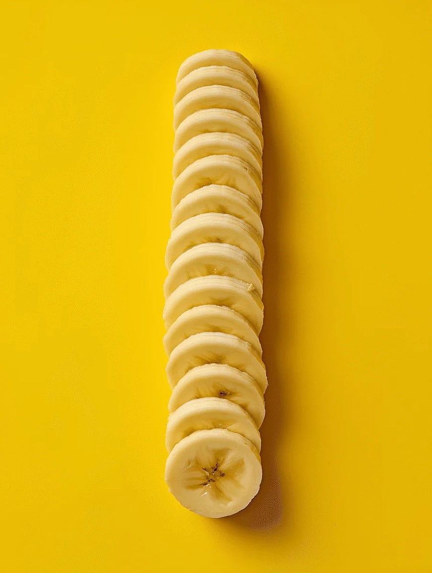 Vertical Stack of Sliced Bananas on Yellow Background