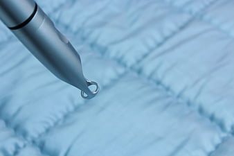 Close-up of a silver medical laser device tip on a blue textured surface