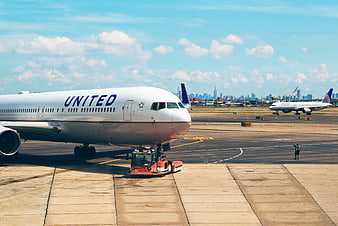 United Airlines plane being towed at airport with city skyline