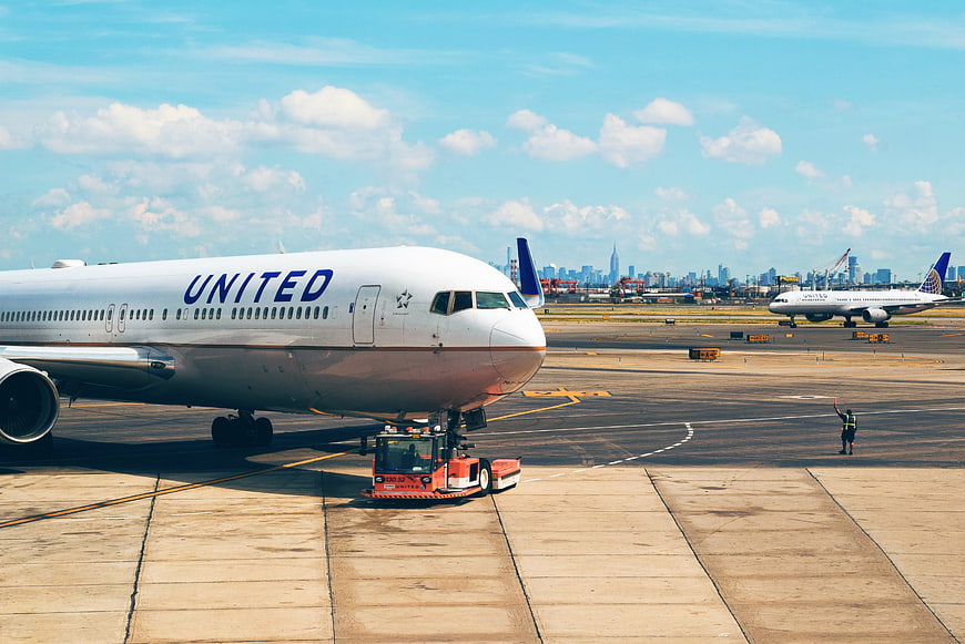 United Airlines plane being towed at airport with city skyline