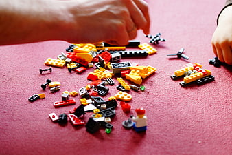 Father and child building with colorful Lego blocks on red surface