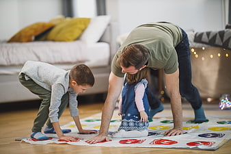 Father and children playing Twister game on living room floor