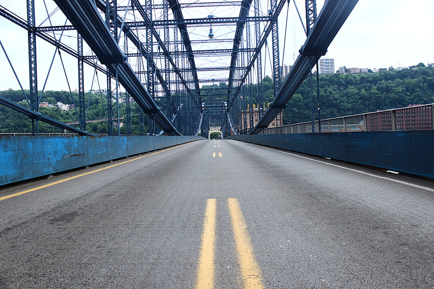 Empty asphalt road on steel truss bridge with city view