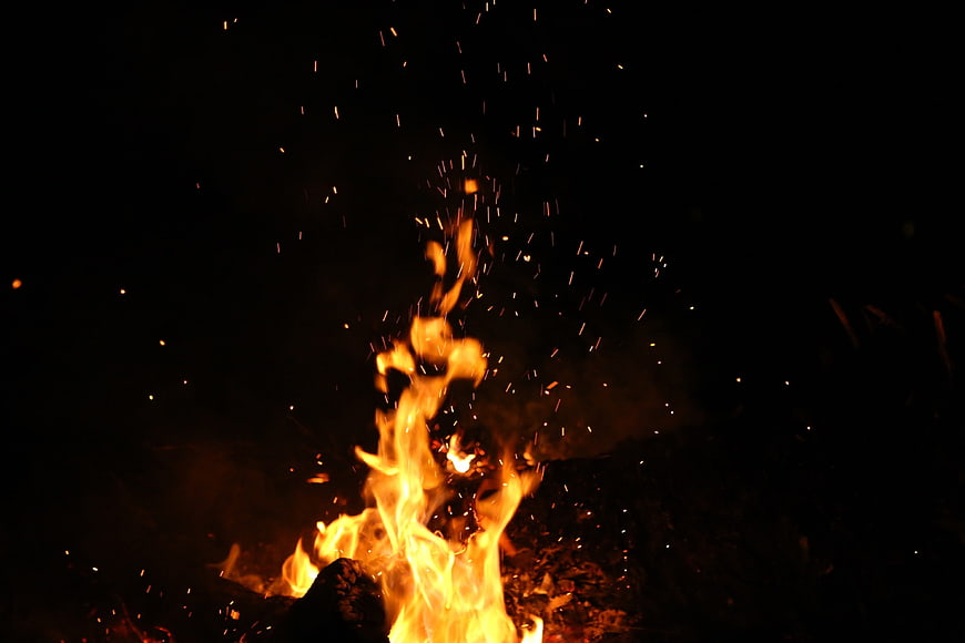 Campfire Flames and Sparks Against Dark Night Sky