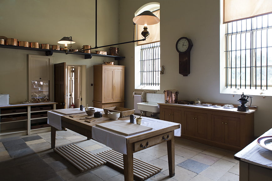 Historic Victorian Kitchen Interior With Copper Utensils And Wooden Table