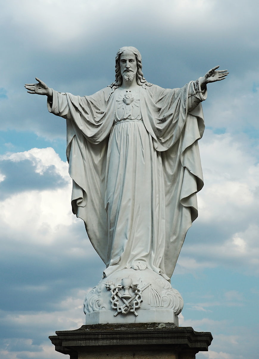 White Statue of Jesus with Open Arms Against Cloudy Sky