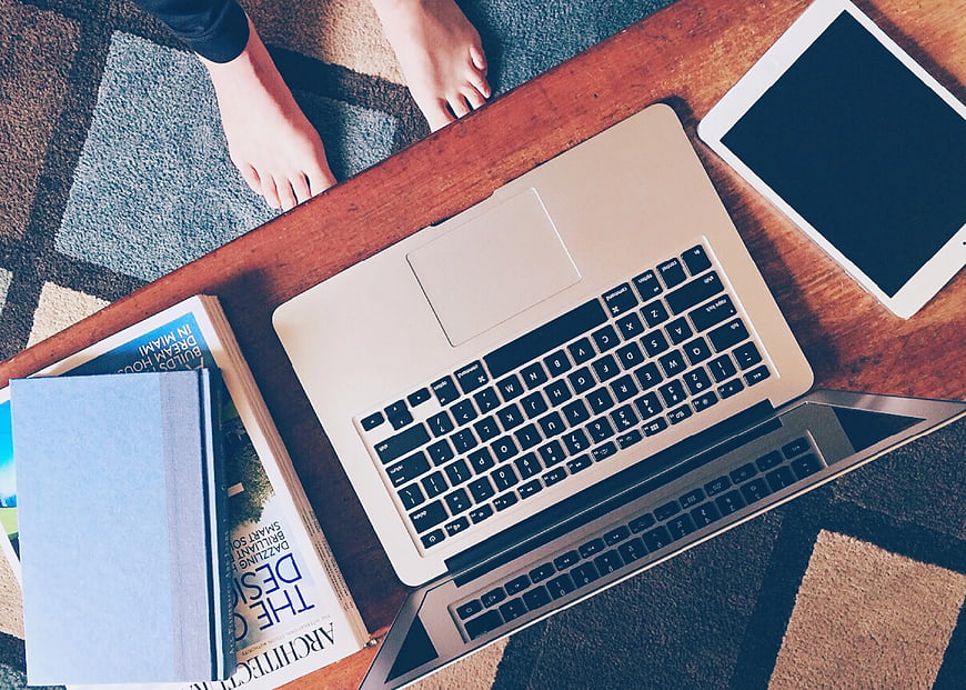Top view of laptop, tablet, and books on wooden table