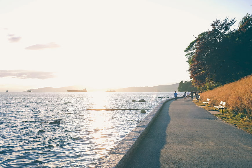 People walking on coastal path at sunset with ocean view