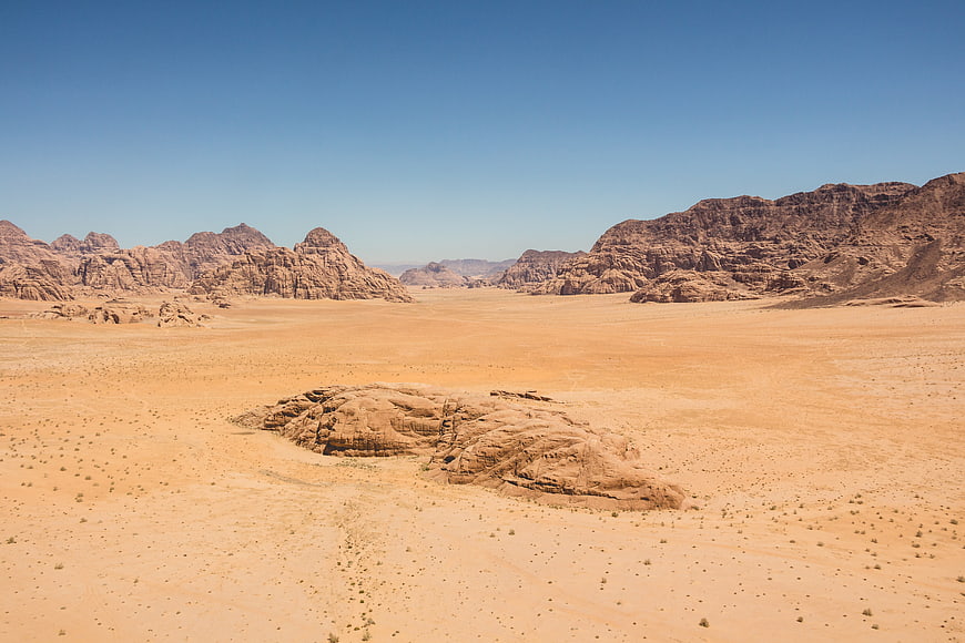 Vast desert landscape with red rock formations and blue sky