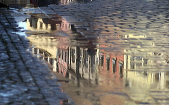 Colorful building reflections in a puddle on a wet cobblestone street