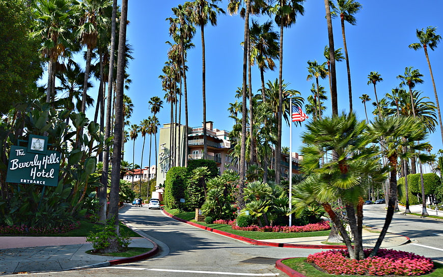 The Beverly Hills Hotel Entrance With Palm Trees And Blue Sky
