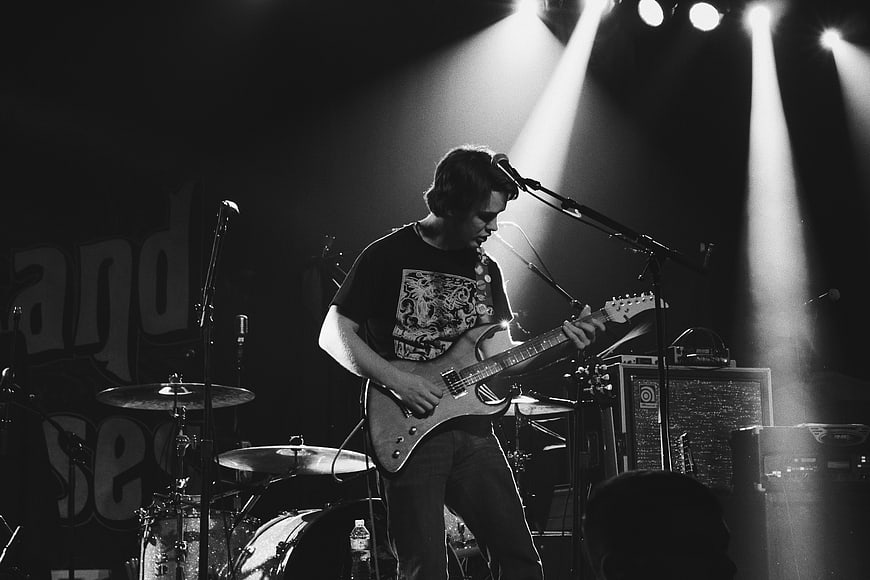 Male Guitarist Performing on Stage in Black and White