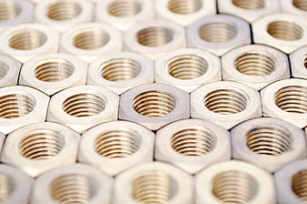 Close-up of silver metal hex nuts arranged in a pattern