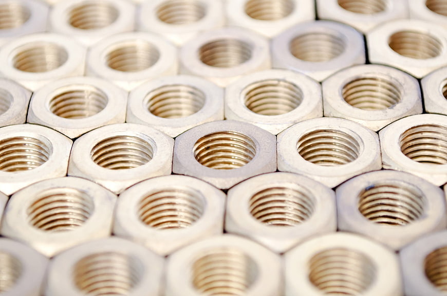 Close-up of silver metal hex nuts arranged in a pattern