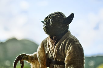 Close-up of Yoda action figure with blurred landscape background