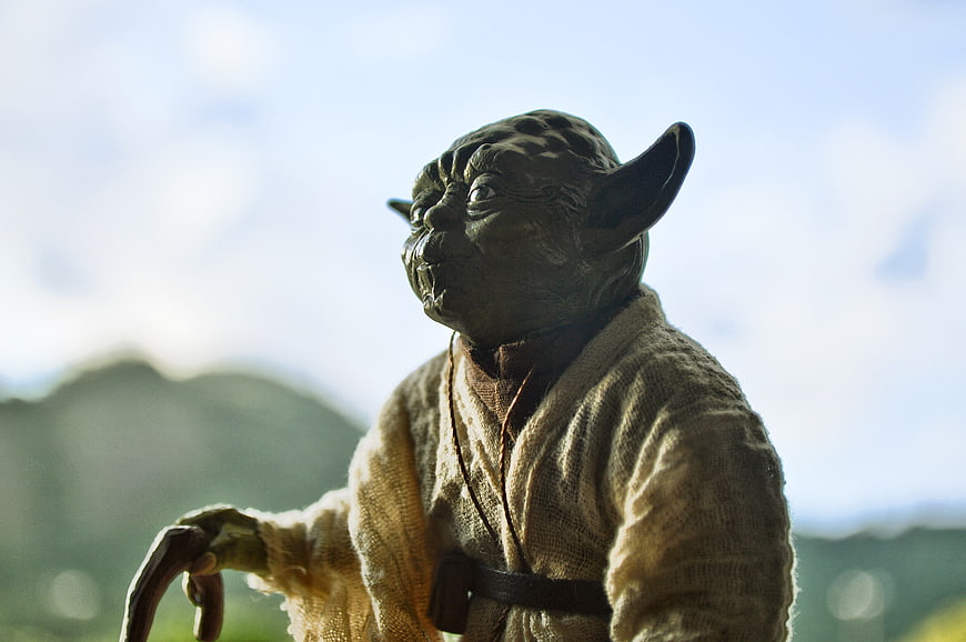 Close-up of Yoda action figure with blurred landscape background