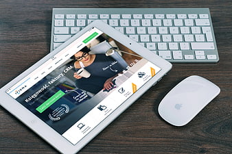 Tablet displaying accounting software on wooden desk with keyboard and mouse