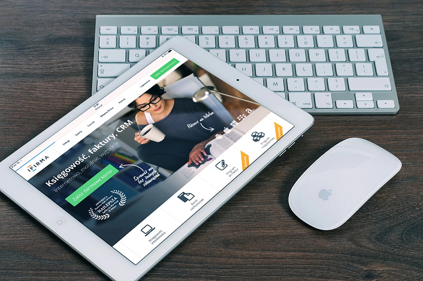 Tablet displaying accounting software on wooden desk with keyboard and mouse
