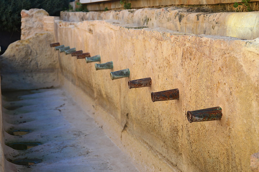 Rusty metal pipes in old stone laundry fountain