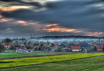 Dramatic HDR landscape of a village at sunset with green fields