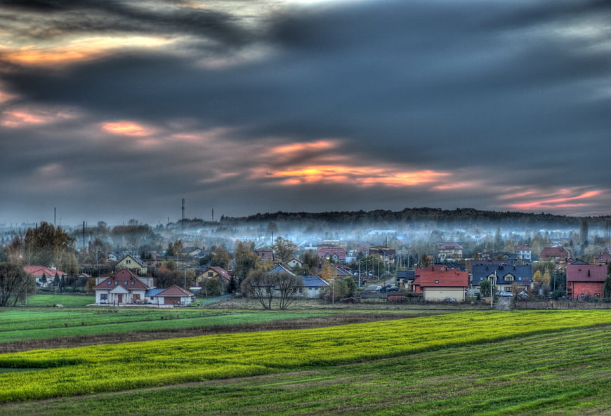 Dramatic HDR landscape of a village at sunset with green fields