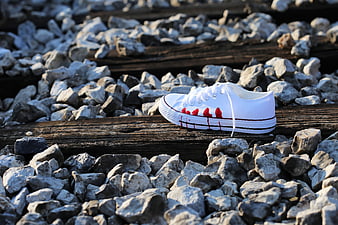White sneaker with red stains on railway tracks