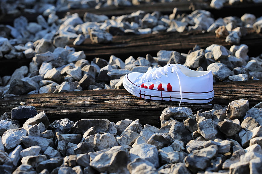 White sneaker with red stains on railway tracks