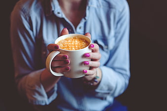 Woman holding warm coffee mug with pink nails