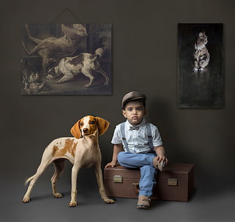Toddler boy and dog sitting on vintage suitcase in studio