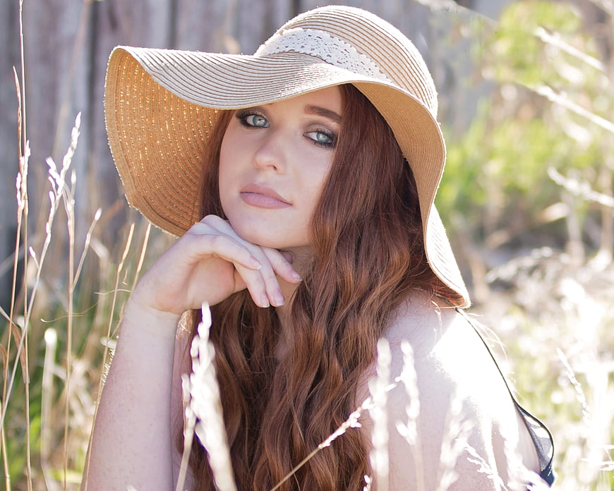 Portrait of a Redhead Woman in a Straw Hat in a Field