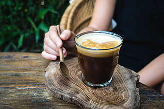 Iced coffee with coconut milk foam on rustic wooden table