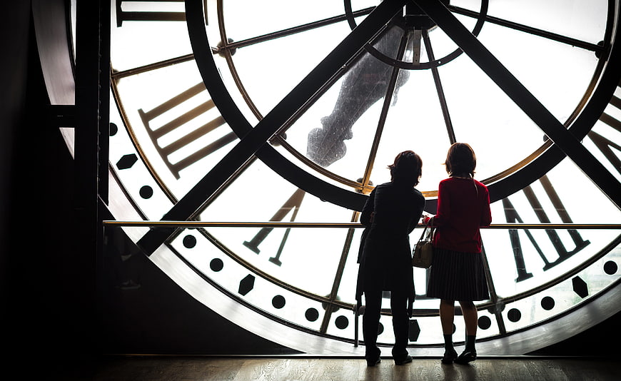 Two women silhouetted against giant clock face at Musée d'Orsay