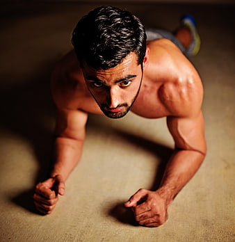 Muscular man performing push-up on concrete floor