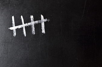 White chalk tally marks on a dark blackboard surface