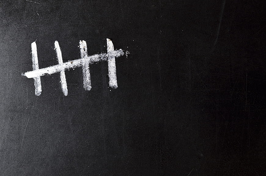 White chalk tally marks on a dark blackboard surface
