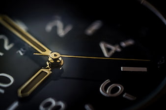 Close-up of black analog watch face with gold hands