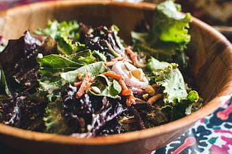 Fresh kale salad with carrots and red onion in wooden bowl