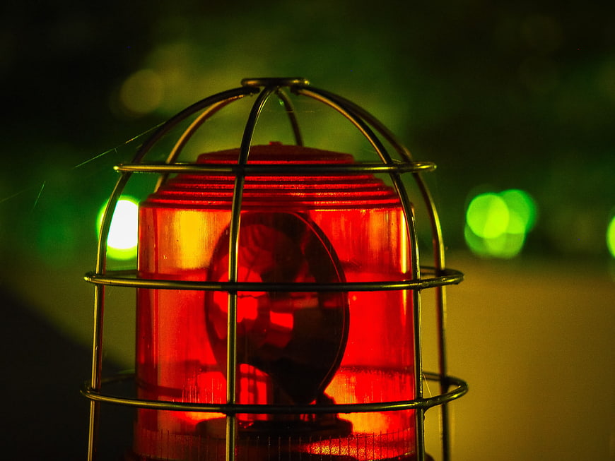 Close-up of red emergency warning light with metal cage