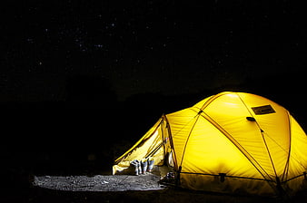 Illuminated yellow camping tent under starry night sky