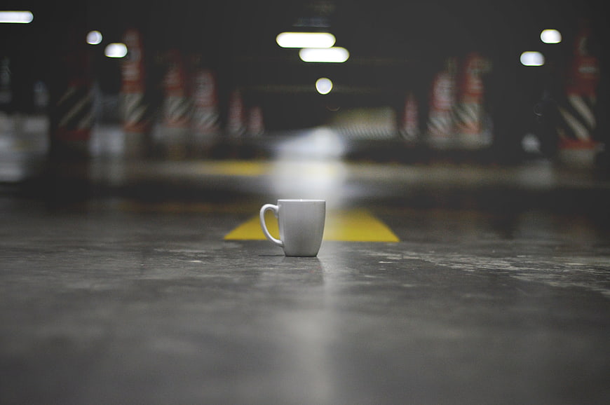 White coffee mug on concrete floor in dark parking garage