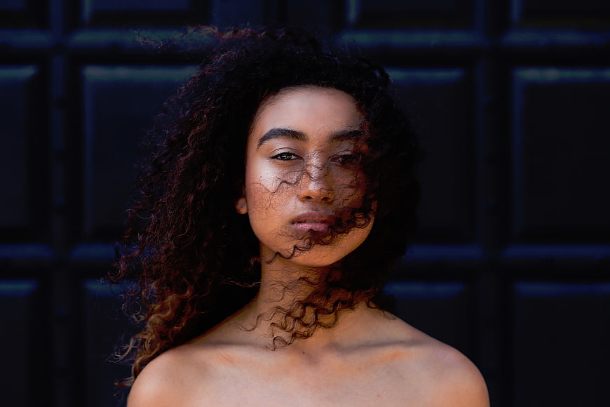 Portrait of woman with curly hair and artistic shadow overlay