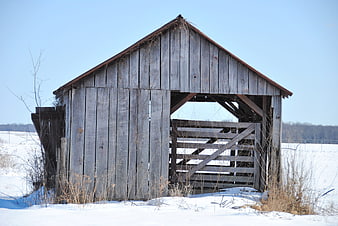 Old weathered wooden barn in snowy winter landscape