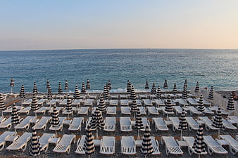 Rows of striped umbrellas and sunbeds on a pebble beach