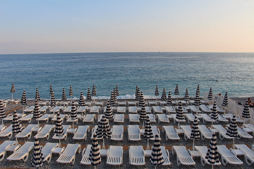 Rows of striped umbrellas and sunbeds on a pebble beach