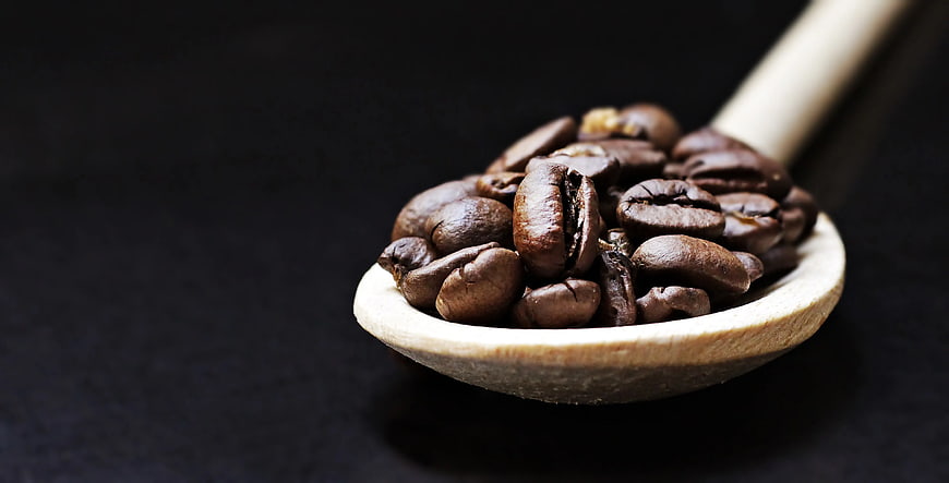 Roasted Coffee Beans in Wooden Spoon on Dark Background