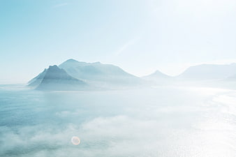 Misty coastal mountain landscape with fog and lens flare