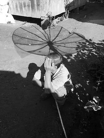 Man resting in shade with umbrella shadow on hot day