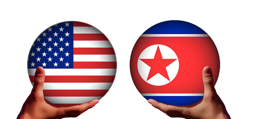 Hands holding USA and North Korea flag balls